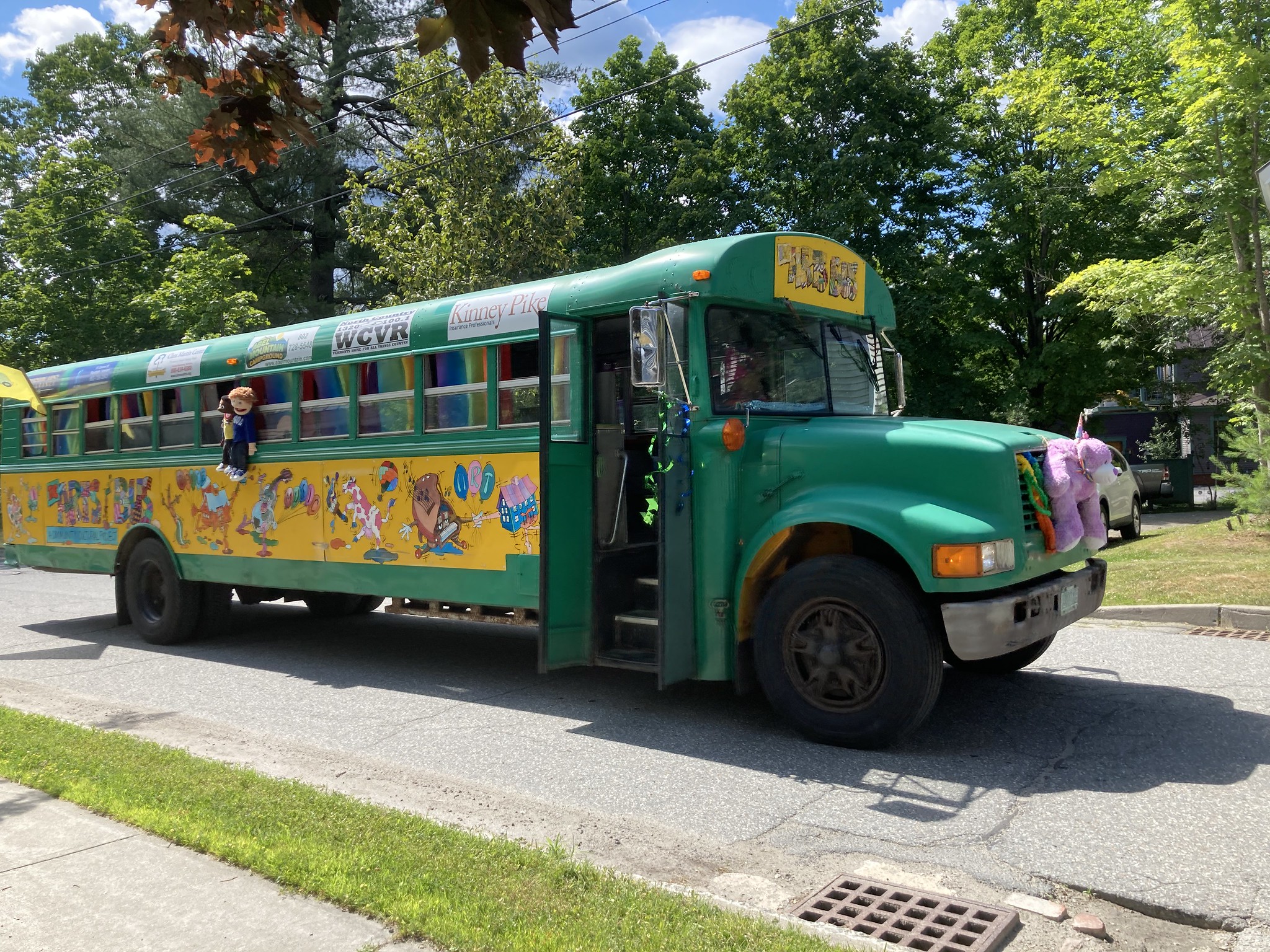 a big green school bus drives in the 4th of july parade