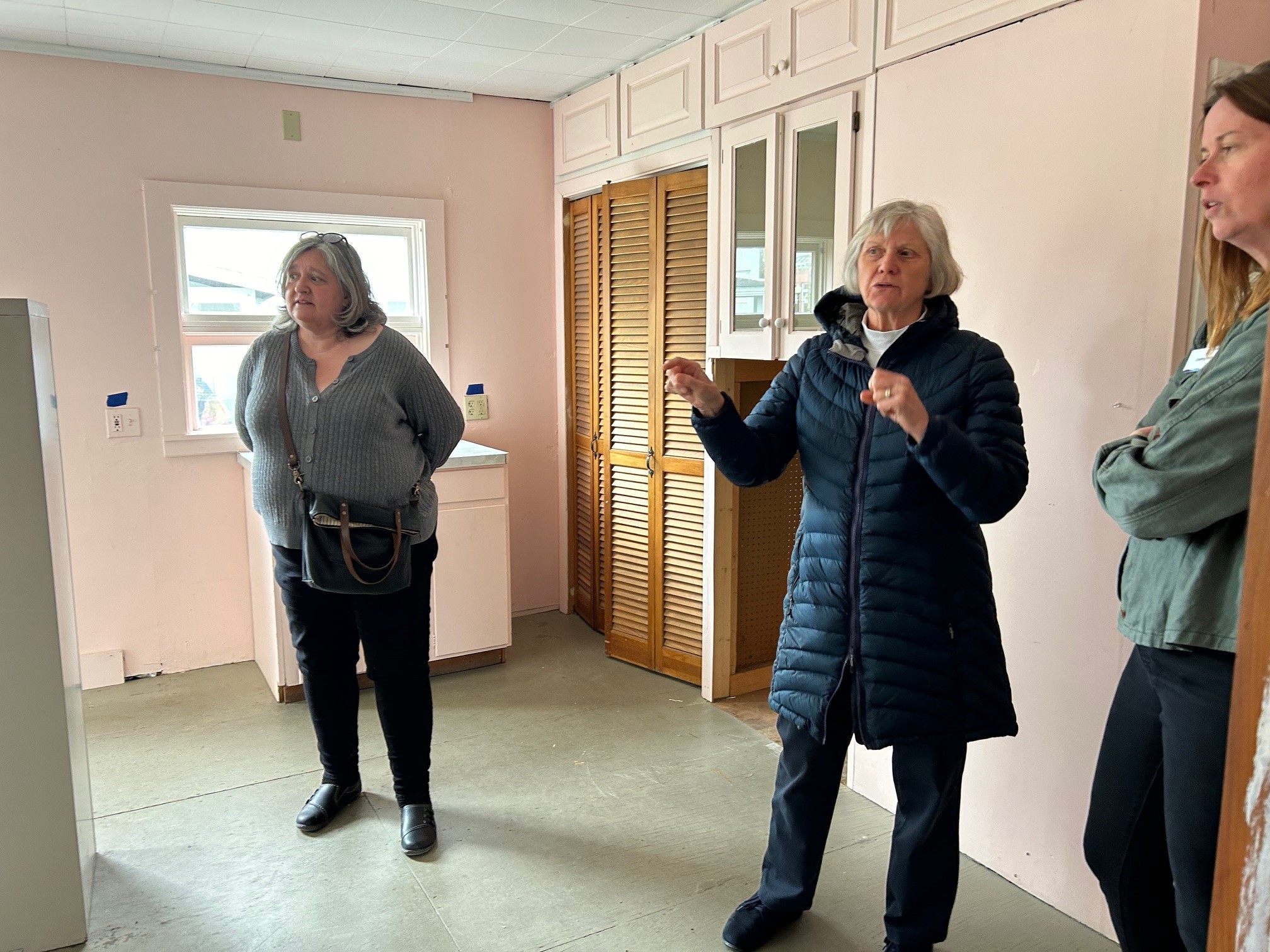 Three woman standing in an empty room discussing a child care center