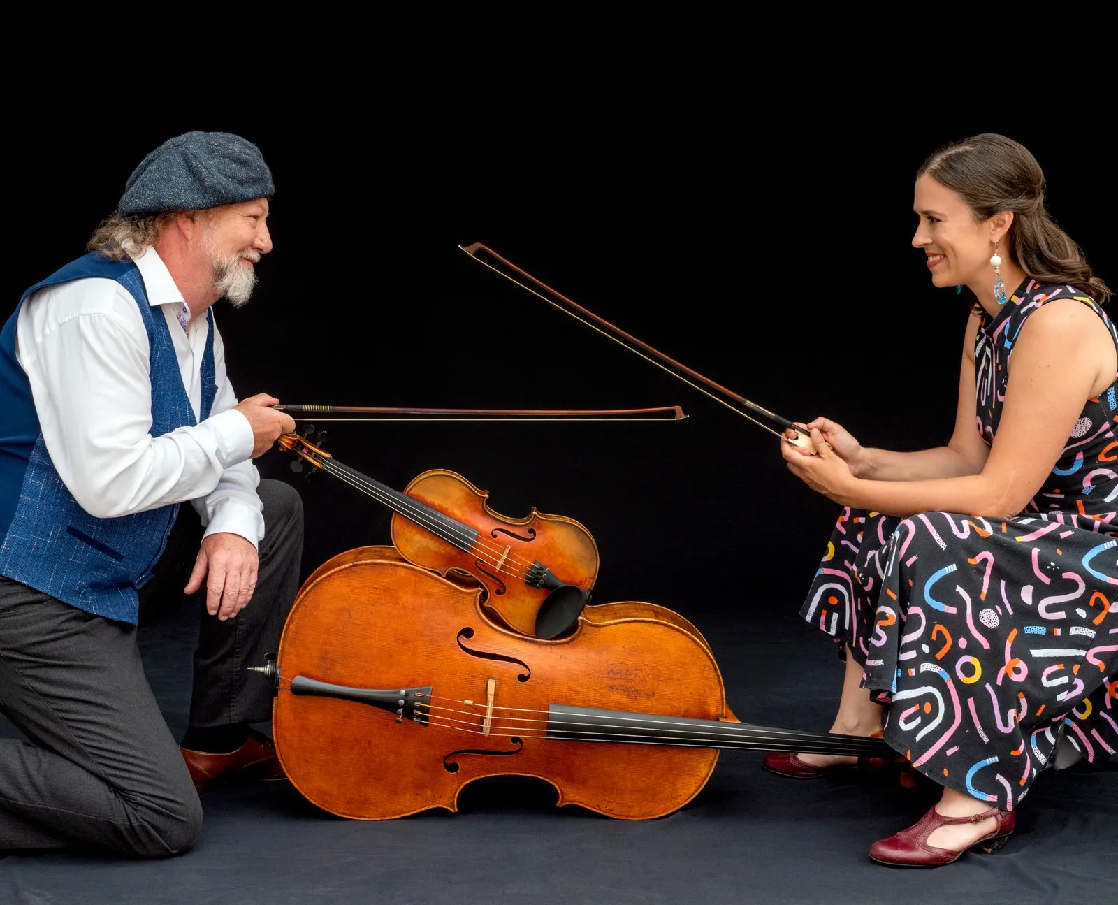 Two laughing musicians holding their string instruments