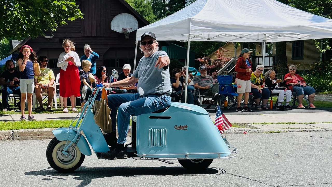man on old blue moped at a parade