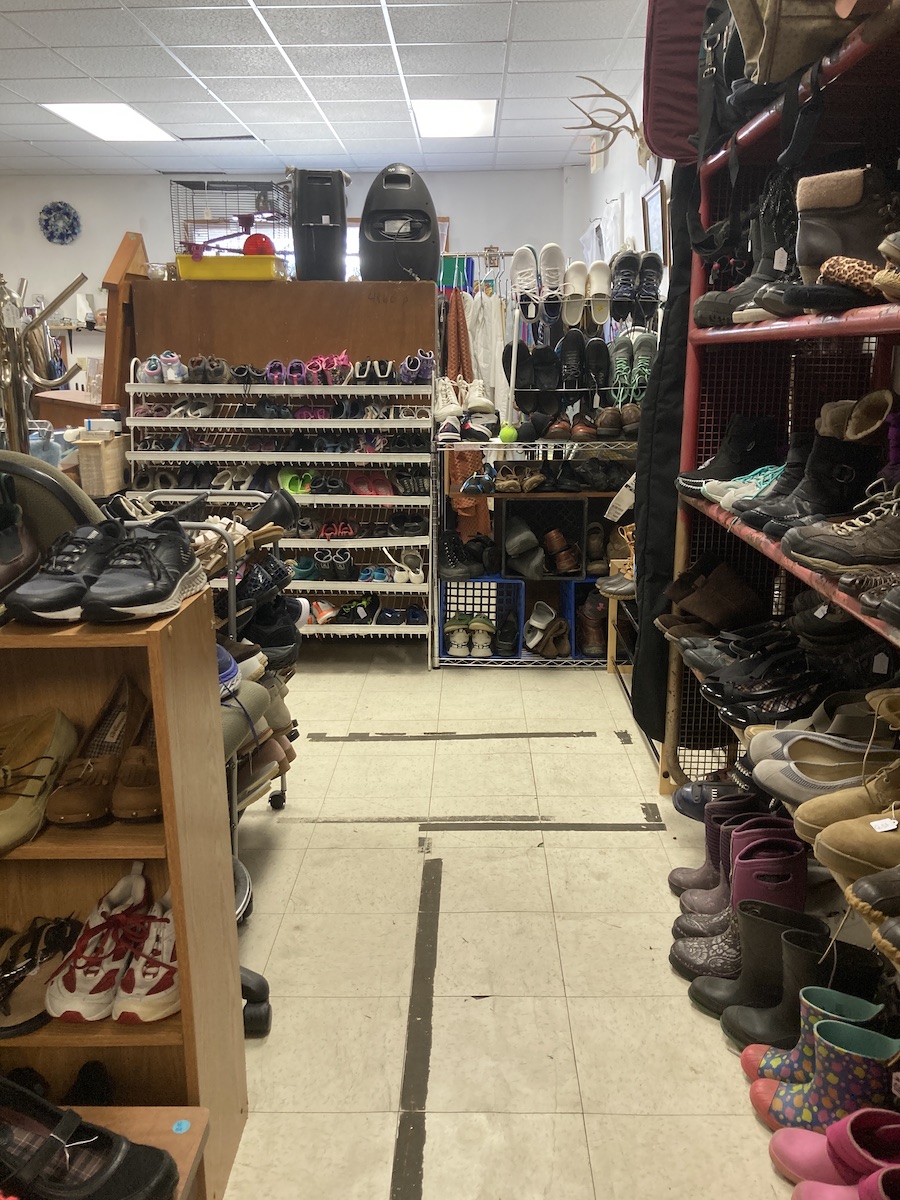 aisle at the trhift store showing many shoes for sale