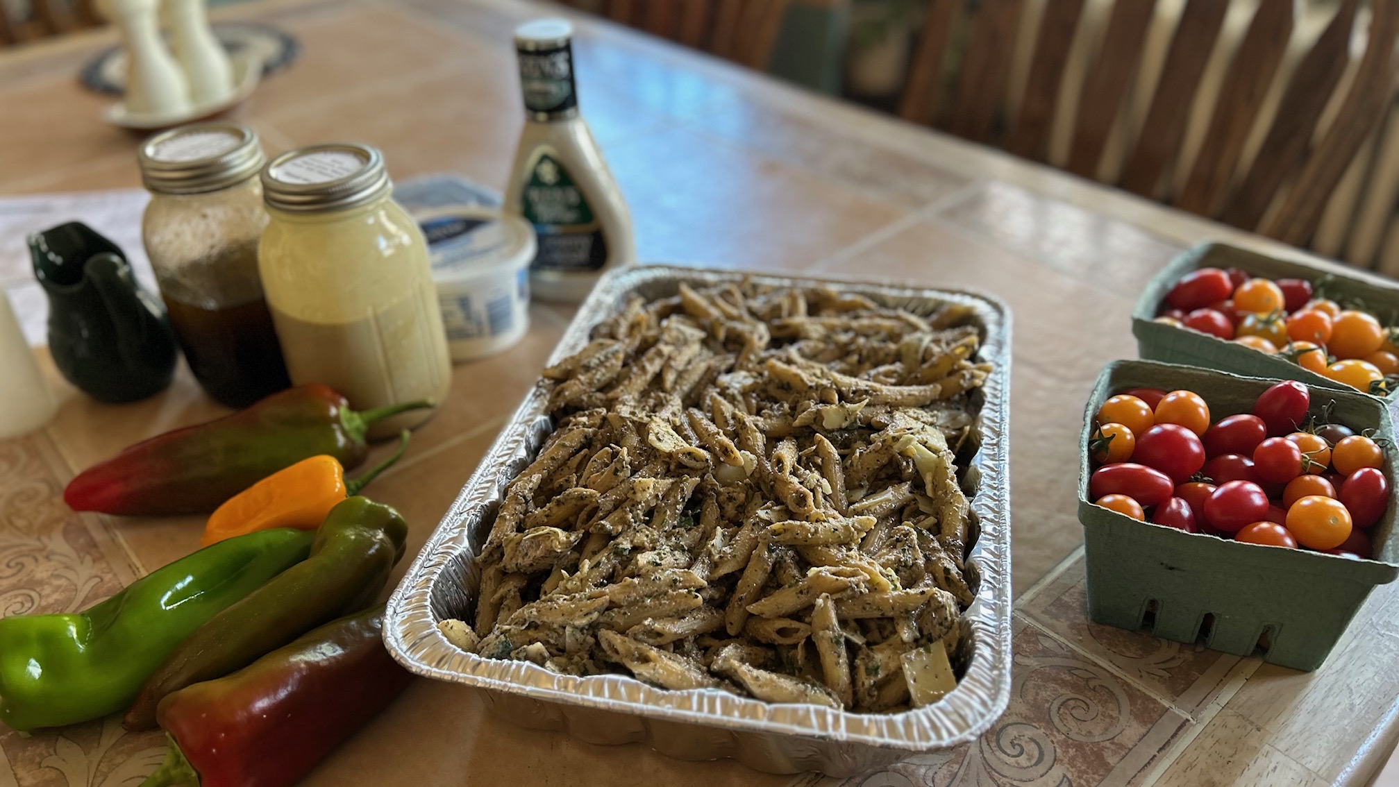 table w pesto pasta and dressings, tomatoes, and pepers