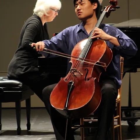 Two performers, one plahying the piano, the other playing the cello 