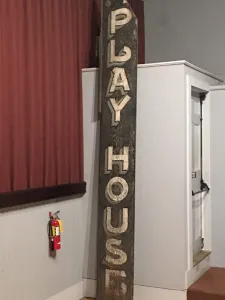 vertical sign, black on white letters, saying Play House