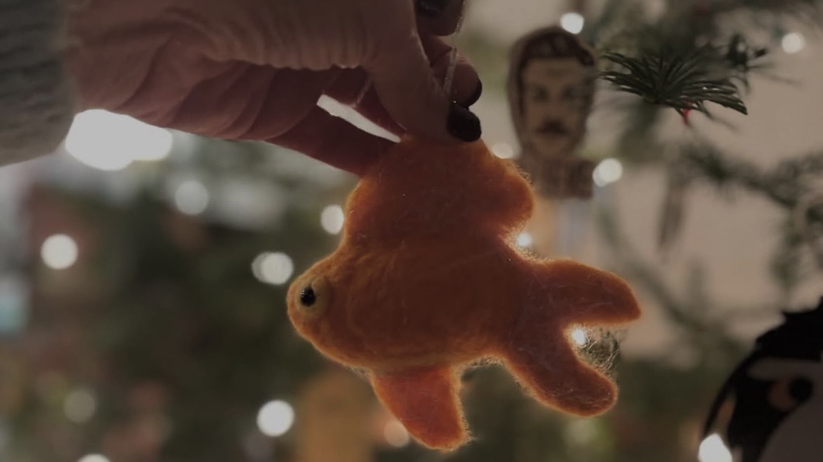 hand holding a felt goldfish in front of what lights