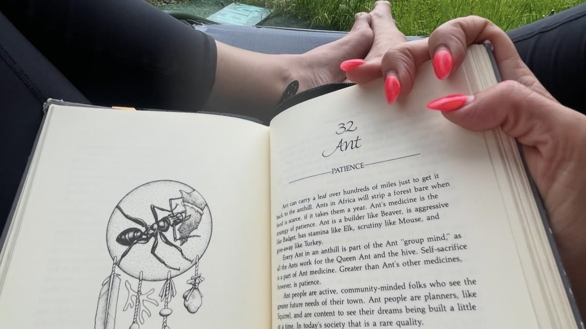 open book hand holding it with long pink nails