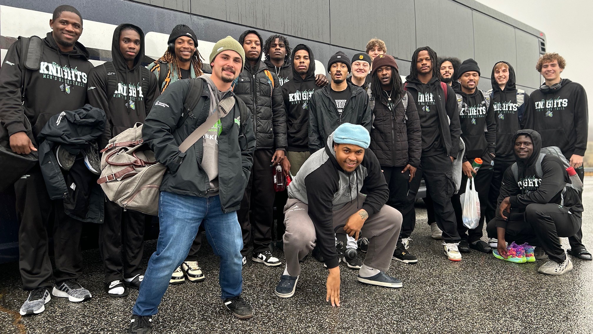 20 person basketball team standing in front of a bus